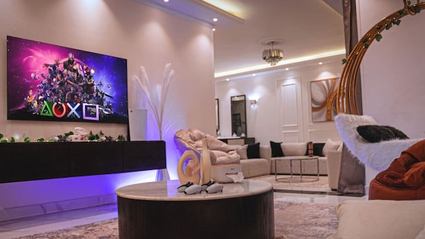 Un saló modern amb un gran televisió de pantalla plana, una taula de centre rodona i un sofà.