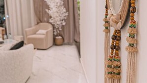 Un saló modern amb un mirall gran, un sofà i una peça decorativa de macramè a la paret.