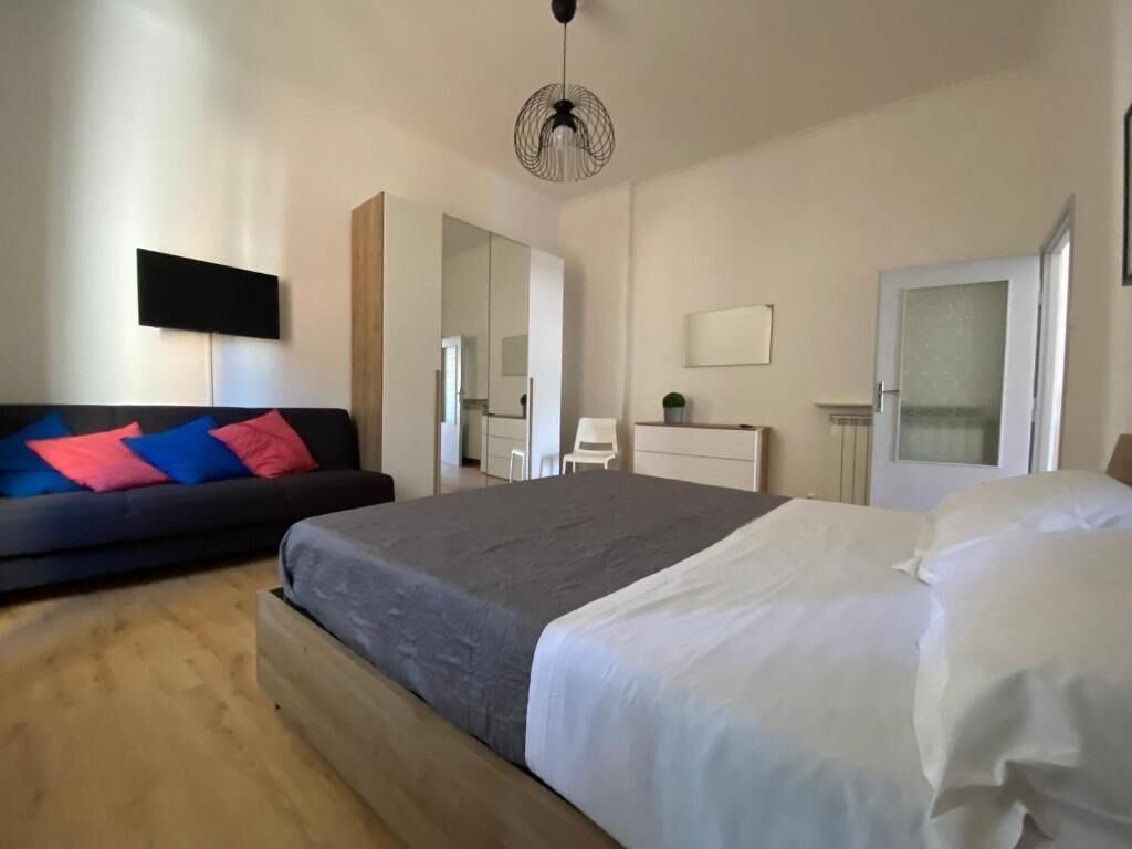 A bedroom with a bed, a sofa, a dresser, a mirror, and a door.
