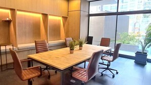 A conference room with a long table, six chairs, and two potted plants. - New Studio apartment with AC, in front of train station Franklin, Santiago City. (Santiago)