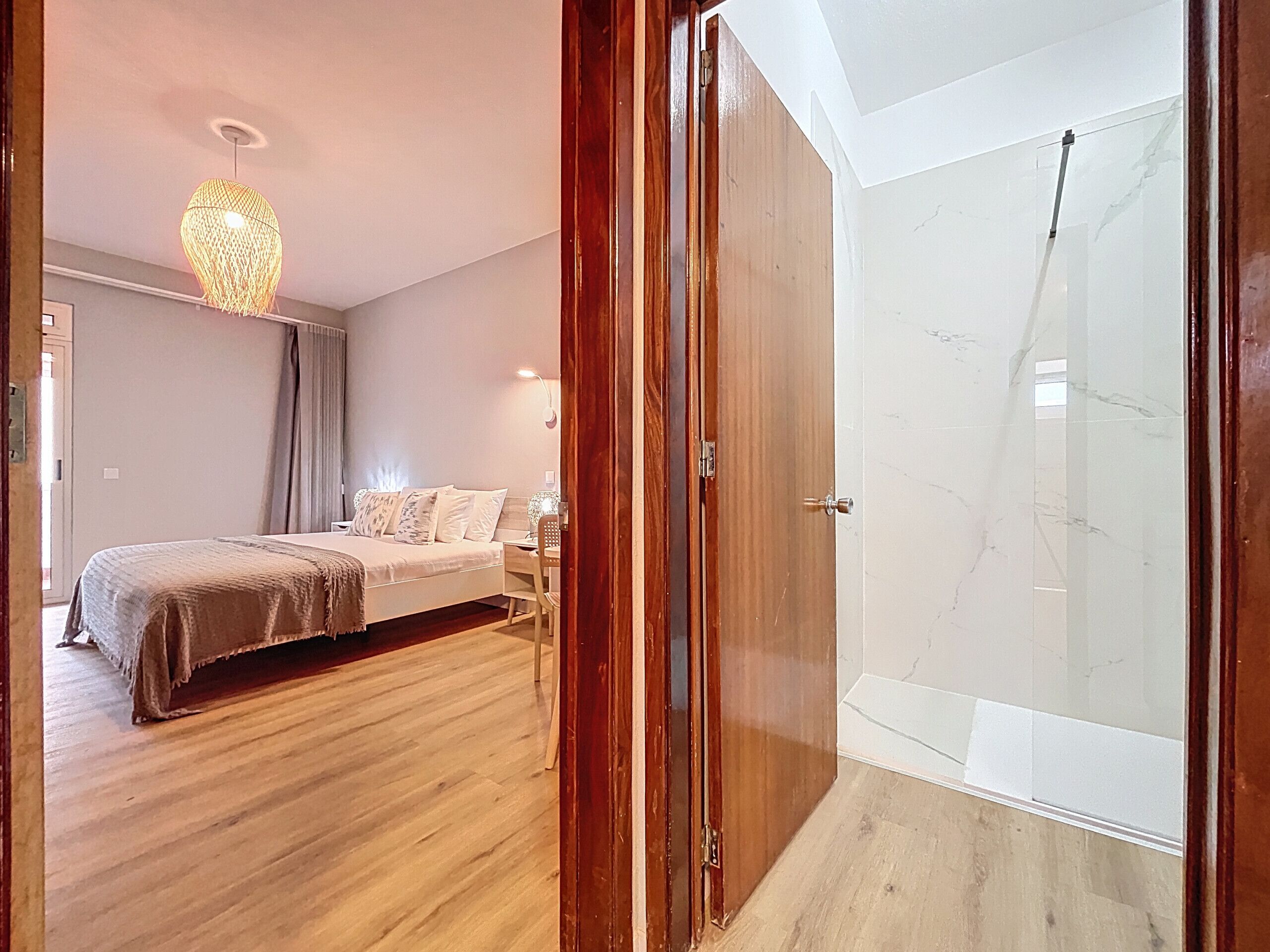 A bedroom with a bed, bedside table, and a hanging light fixture.