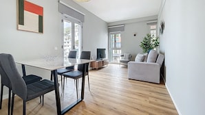 Una sala de estar moderna con comedor, ventanas amplias y vista a la ciudad.