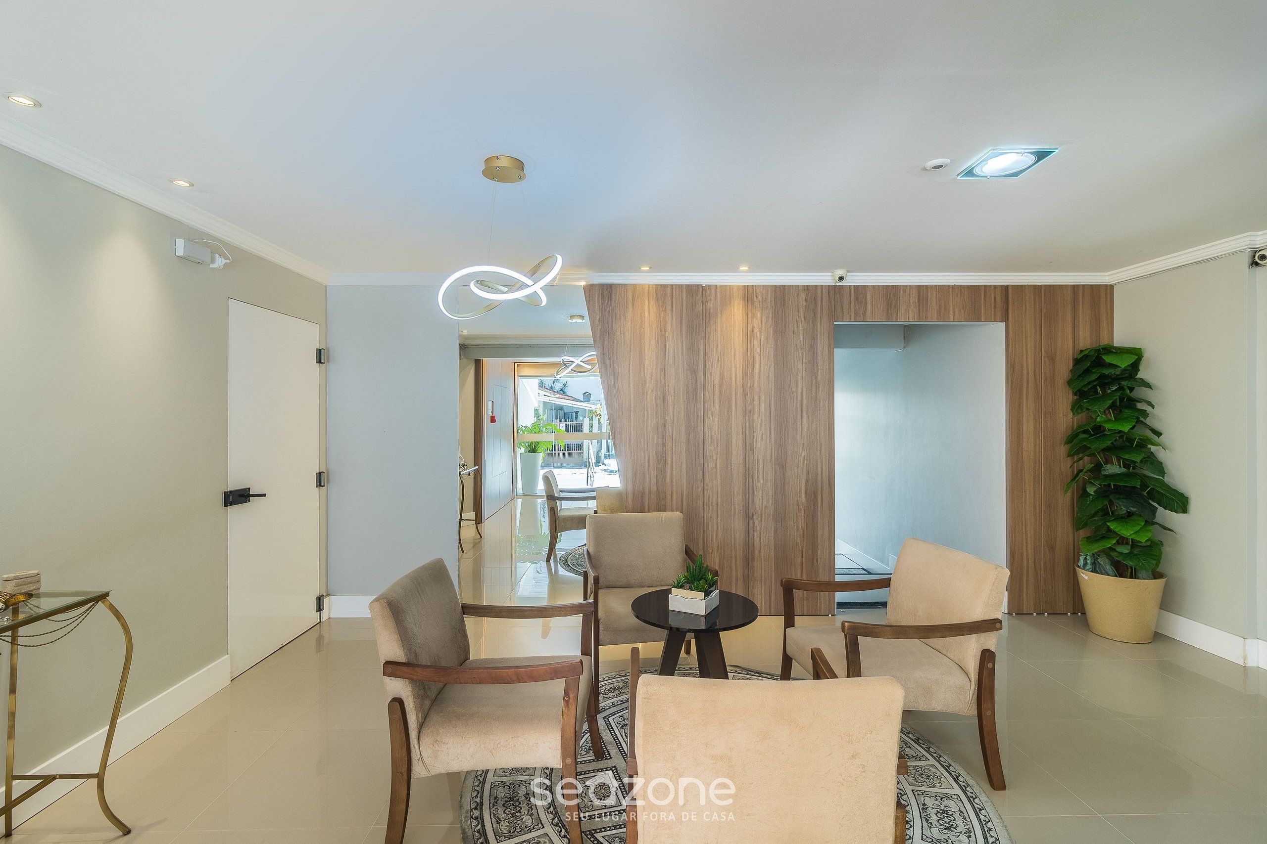 Una sala de estar moderna con una mesa de centro de vidrio, sofás color beige y una pared de acento de madera.