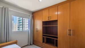 A bedroom with a bed, a window with curtains, and wooden wardrobes with multiple compartments. - Apt in Downtown BC 350m From the Beach Pae1002 (Balneário Camboriú)