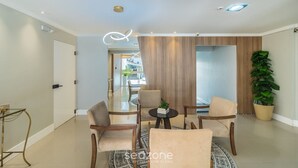 A modern living room with a glass coffee table, beige sofas, and a wooden accent wall. - Apt in Downtown BC 350m From the Beach Pae1002 (Balneário Camboriú)