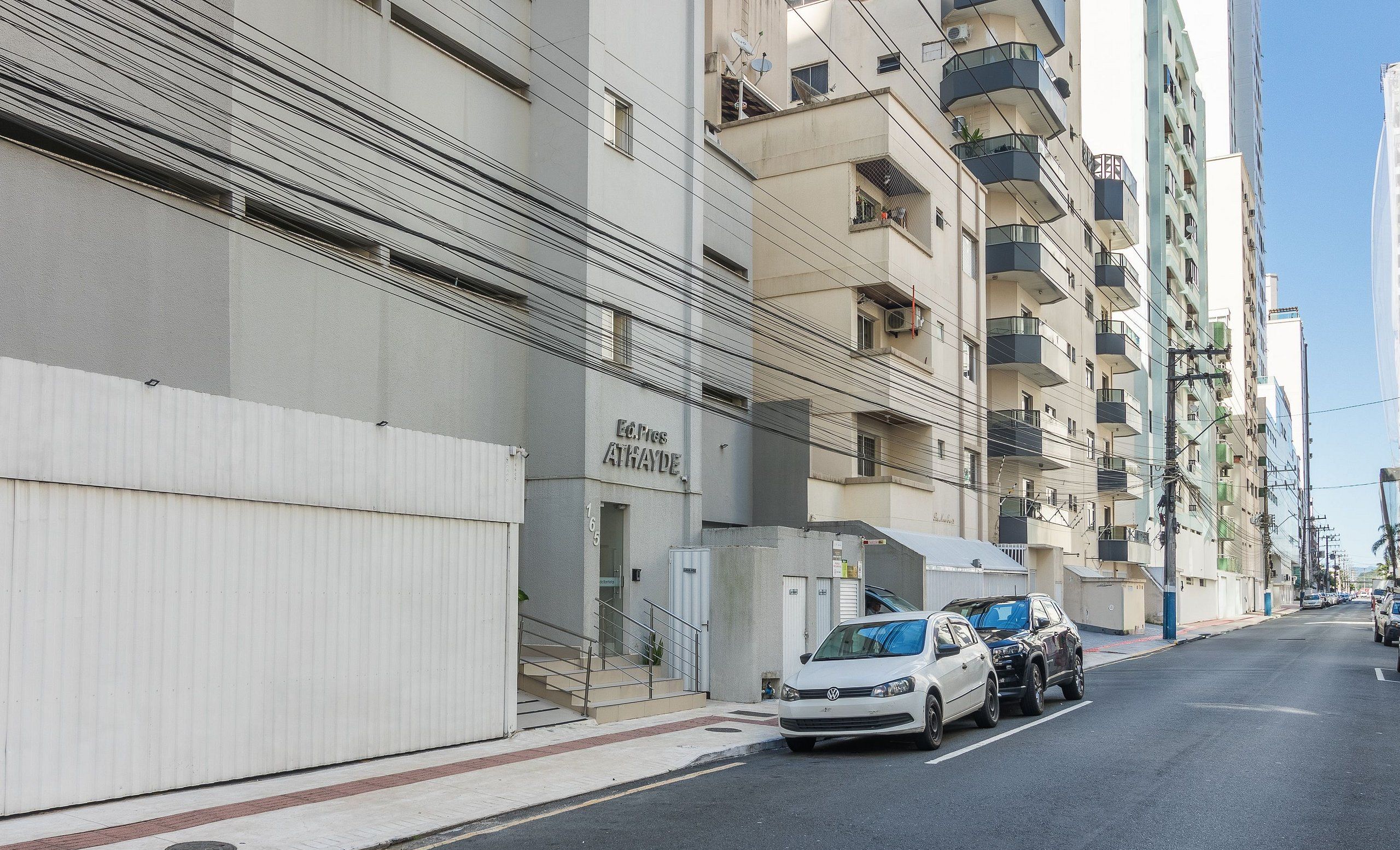 Un edificio residencial de varios pisos con balcones y una entrada protegida por una reja.