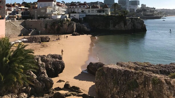 Une ville côtière avec des bâtiments qui bordent la plage, une plage de sable et des affleurements rocheux.