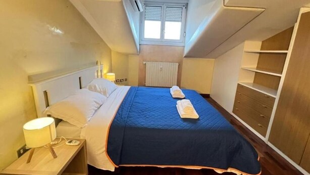 A bedroom with a bed, bedside tables, a window, a radiator, and a wardrobe. - Bergamoinhome (Bergamo)