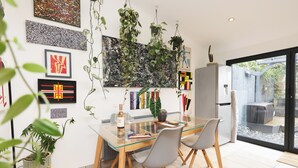 Et moderne spiseområde med et glasbord, to stole og hængende planter.