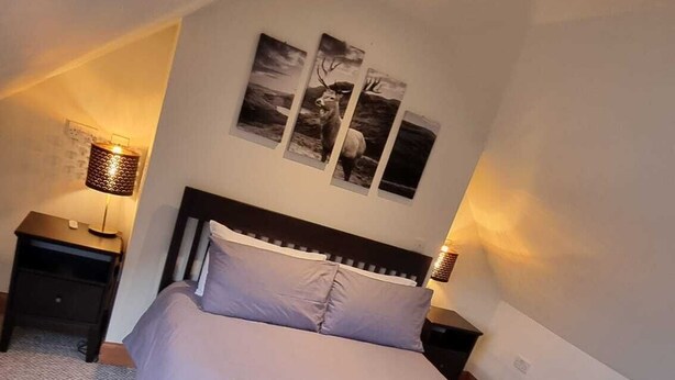 A bedroom with a bed, a nightstand, a wall-mounted lamp, and a ceiling light. - A Spacious 3-Bedroom Retreat at the Gateway to the Highlands (Inverlochy)