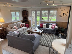 Un salon chaleureux avec deux canapés, une table basse et une cheminée. Une grande fenêtre offre une vue sur l’extérieur.