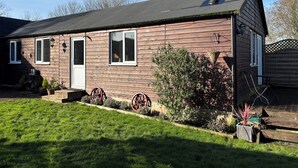 Una casa de madera con techo oscuro, una chimenea y un pequeño porche frontal con escalones.