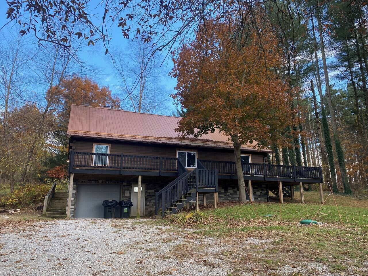 Une cabane à deux étages, avec des fondations en pierre, un toit en métal et un balcon au deuxième étage.