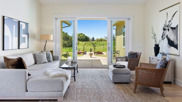 A spacious living room with a large sofa, a coffee table, and a chair. There is a sliding glass door leading to an outdoor patio area with a view of greenery. - Beautiful & dog-friendly vacation retreat in the heart of Sonoma Country (Santa Rosa)