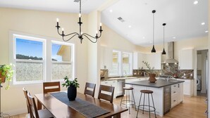 A modern kitchen with a central island, white cabinetry, and a large window providing a view of the outdoors. - Beautiful & dog-friendly vacation retreat in the heart of Sonoma Country (Santa Rosa)
