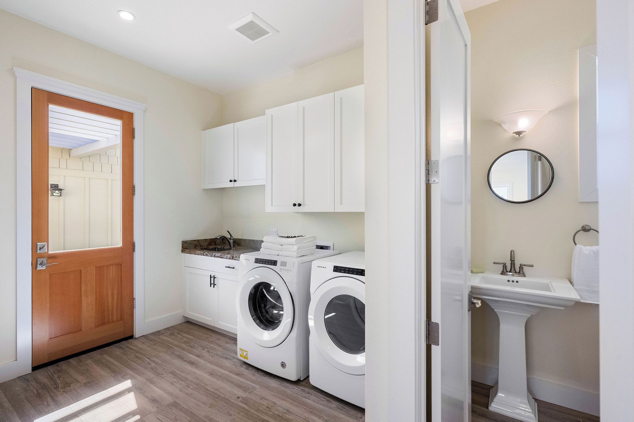 A laundry room with a washing machine, dryer, and a sink with a mirror.