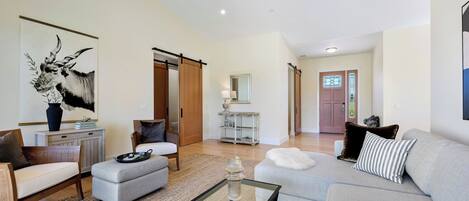 Un salón amplio con sofá, sillones, una mesa de centro y un cuadro grande.