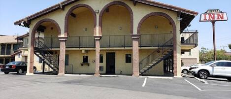 A two-story building with a yellow facade and three arches on the ground floor. There is a sign for 'Sierra Inn' on the right.