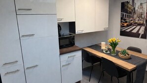 Une cuisine moderne avec des meubles blancs, un plan de travail en bois et un coin repas comprenant une table et des chaises.