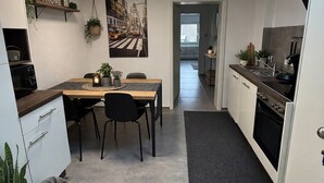 Une cuisine moderne avec un coin repas, une verrière et une vue sur l’extérieur.
