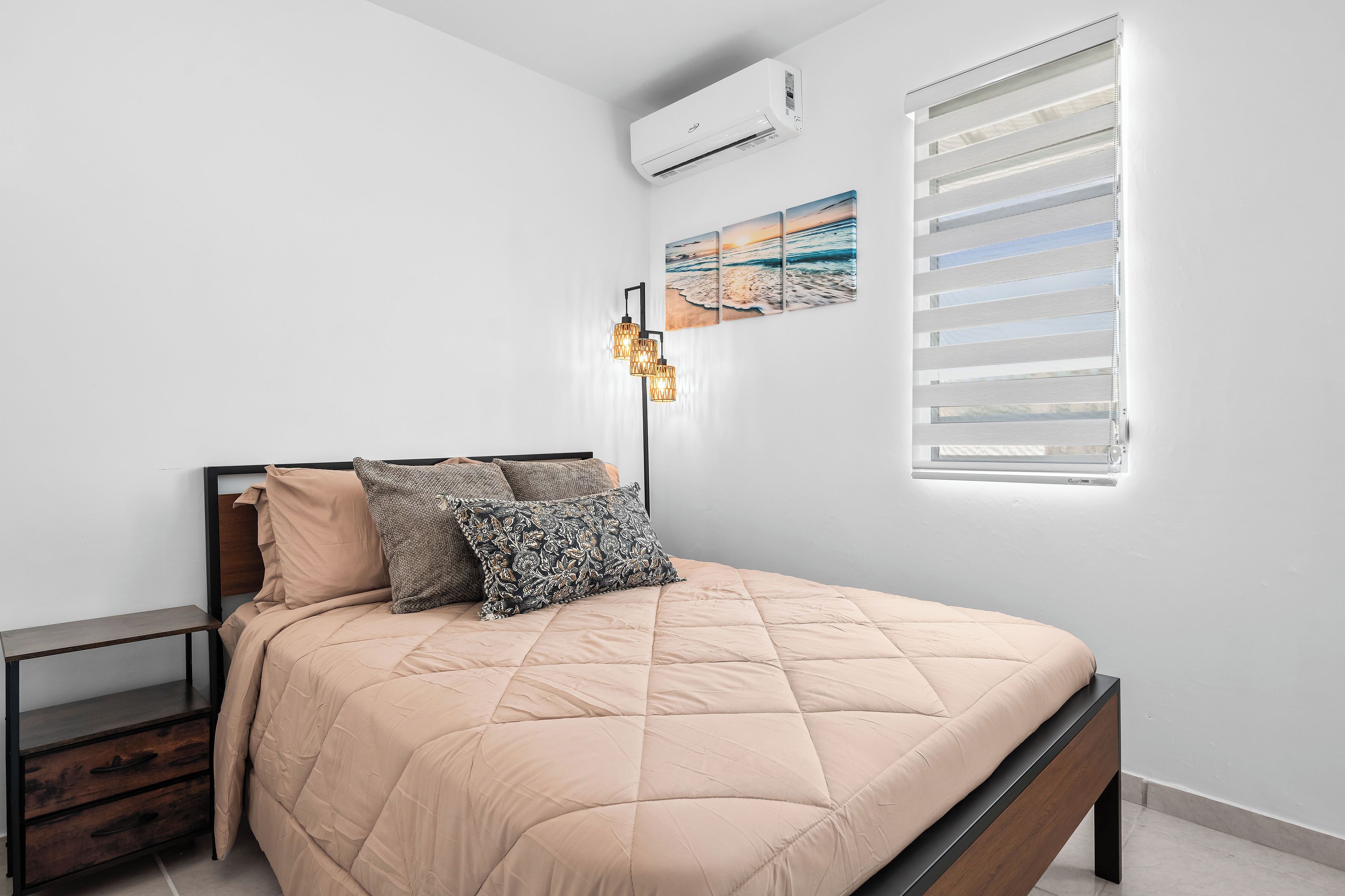 Un dormitorio con cama, mesita de noche y aire acondicionado instalado en la pared.