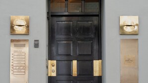A black door with brass handles, flanked by two plaques and a keyhole. - The Darling (Copenhagen)