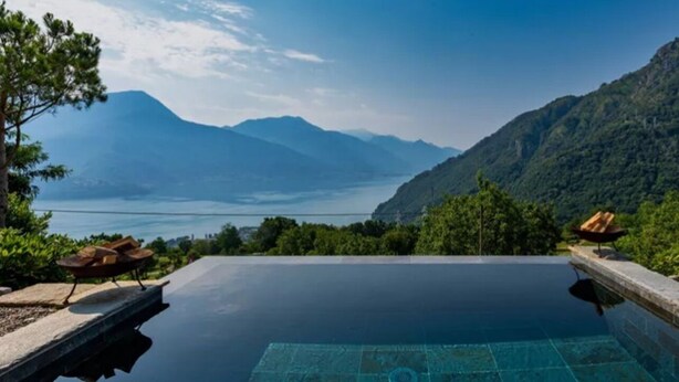 Une piscine à débordement offrant une vue sur un lac et des montagnes.