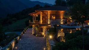 Une maison en pierre dotée d’un porche abrité et d’une piscine, entourée de montagnes.