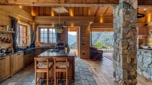 Une cuisine rustique avec des poutres en bois, des éléments en pierre et une vue sur les montagnes.