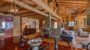 Un chalet spacieux avec un haut plafond en bois, une cheminée en pierre et un coin salon confortable.