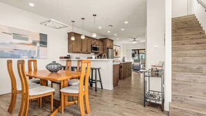 A modern kitchen with wooden cabinets, a central island, and pendant lighting.