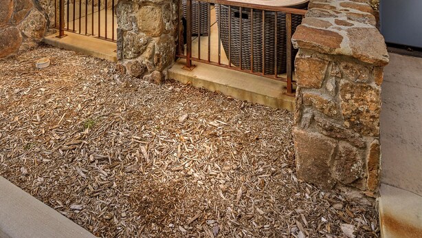 A two-story building with a stone exterior, a balcony with metal railings, and a seating area with a fire pit.