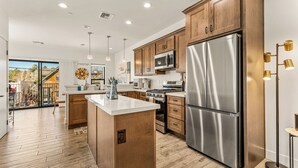 A modern kitchen with wooden cabinets, stainless steel appliances, and a large island.