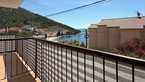 A balcony with a view of a coastal area, including a body of water and a hilly landscape. - Apartments Benzia (Marina)