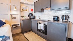 A compact kitchen with a microwave, toaster, kettle, and a small oven.