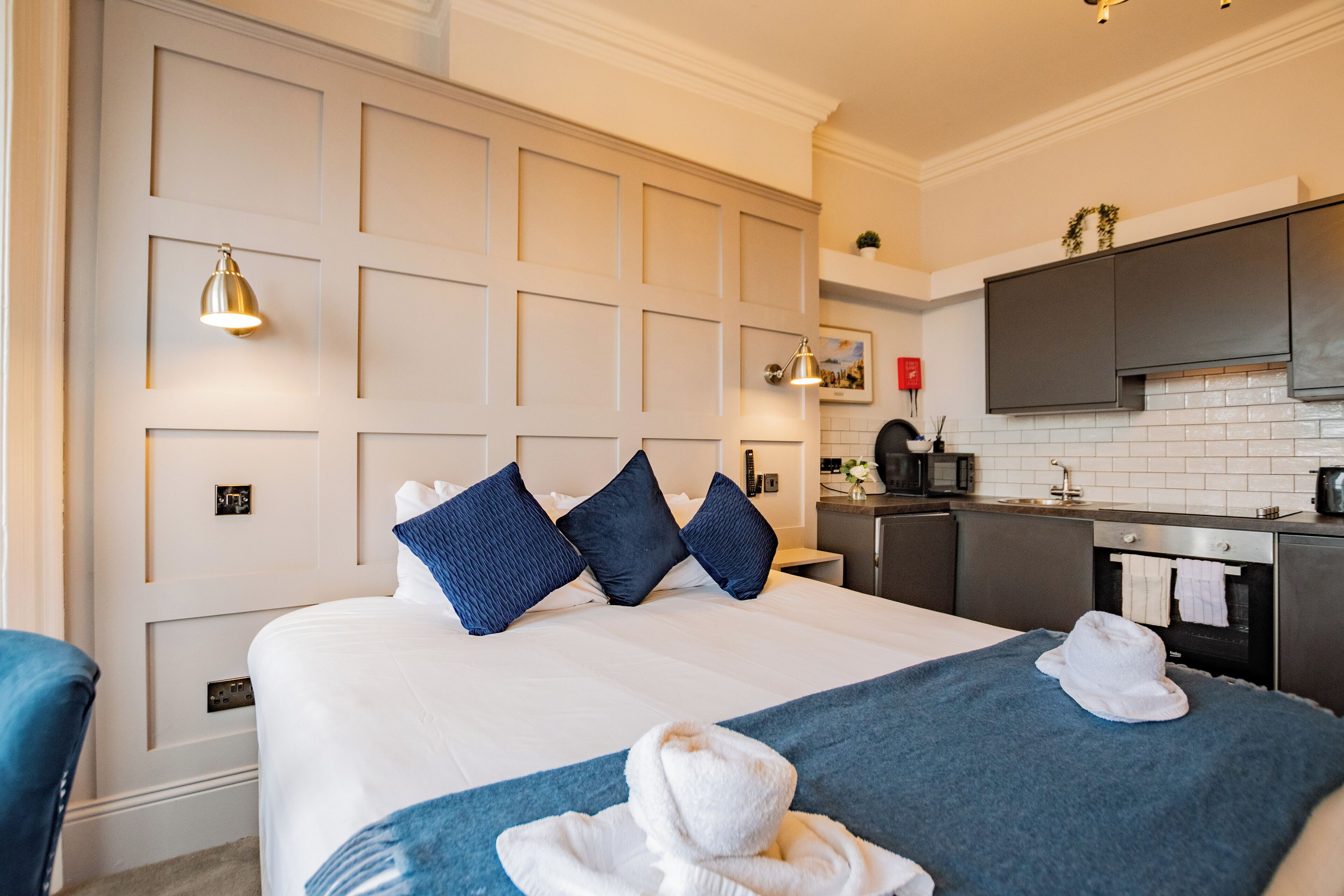 Una habitación de hotel con una cama grande, un escritorio y una kitchenette.