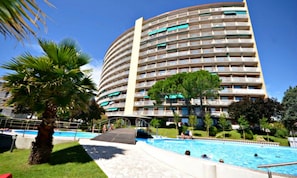 Ein mehrstöckiges Hotel mit Poolbereich, einschließlich Sprungbrett und kleiner Brücke über dem Pool.
