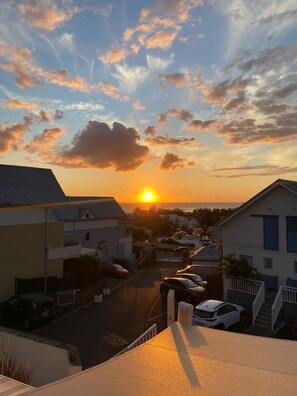 A residential street at sunset with houses and parked cars. - Cosy apartment with sea view terrace in the heart of La Saline les bains (Saint-Paul)