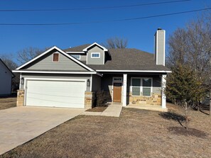 Une maison à deux étages avec un garage, des fondations en pierre et une cheminée.