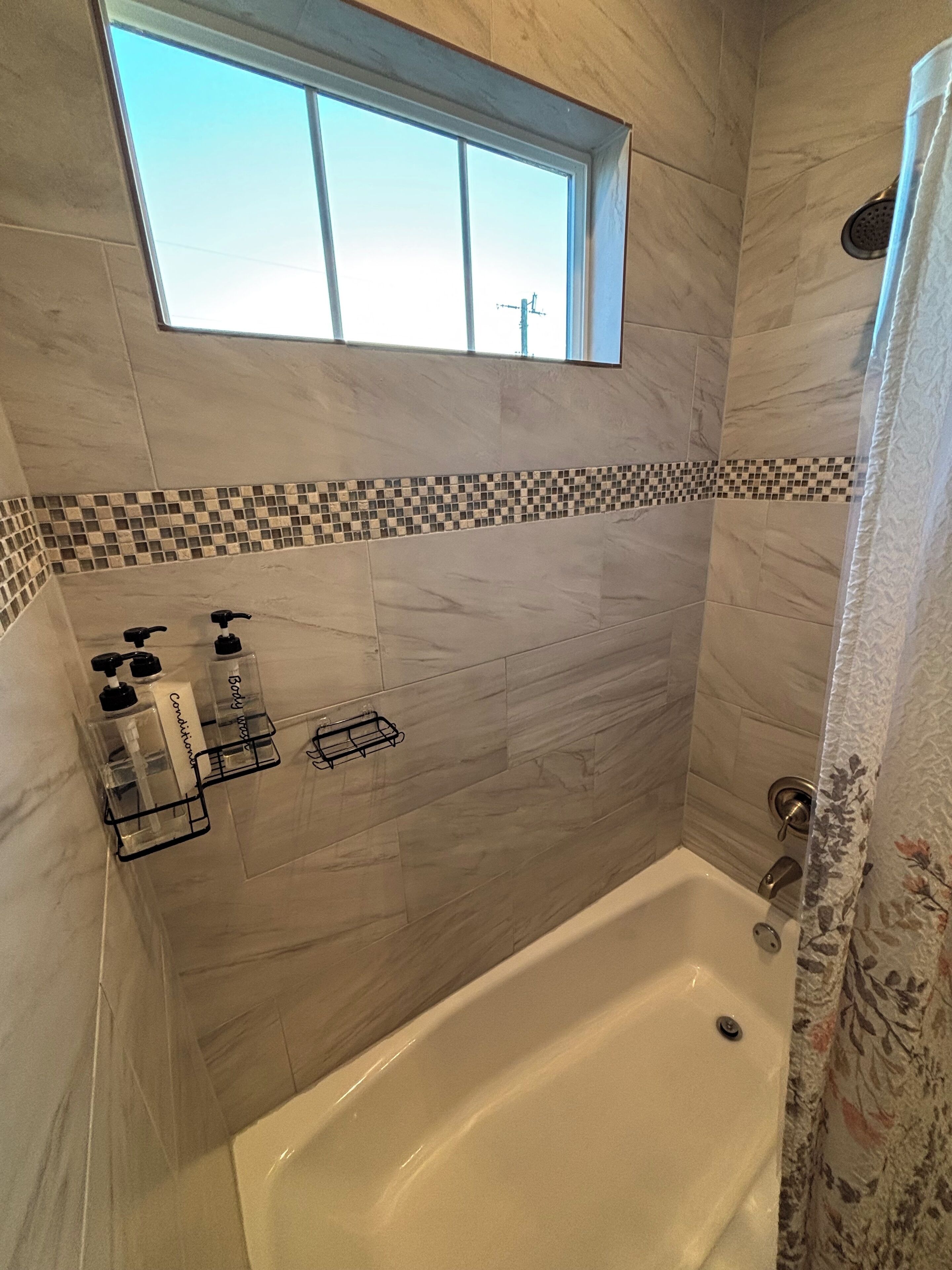 A bathroom with a bathtub, a window, and a shower curtain.
