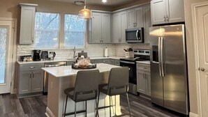 Cocina moderna con una isla central, electrodomésticos de acero inoxidable y una lámpara colgante.