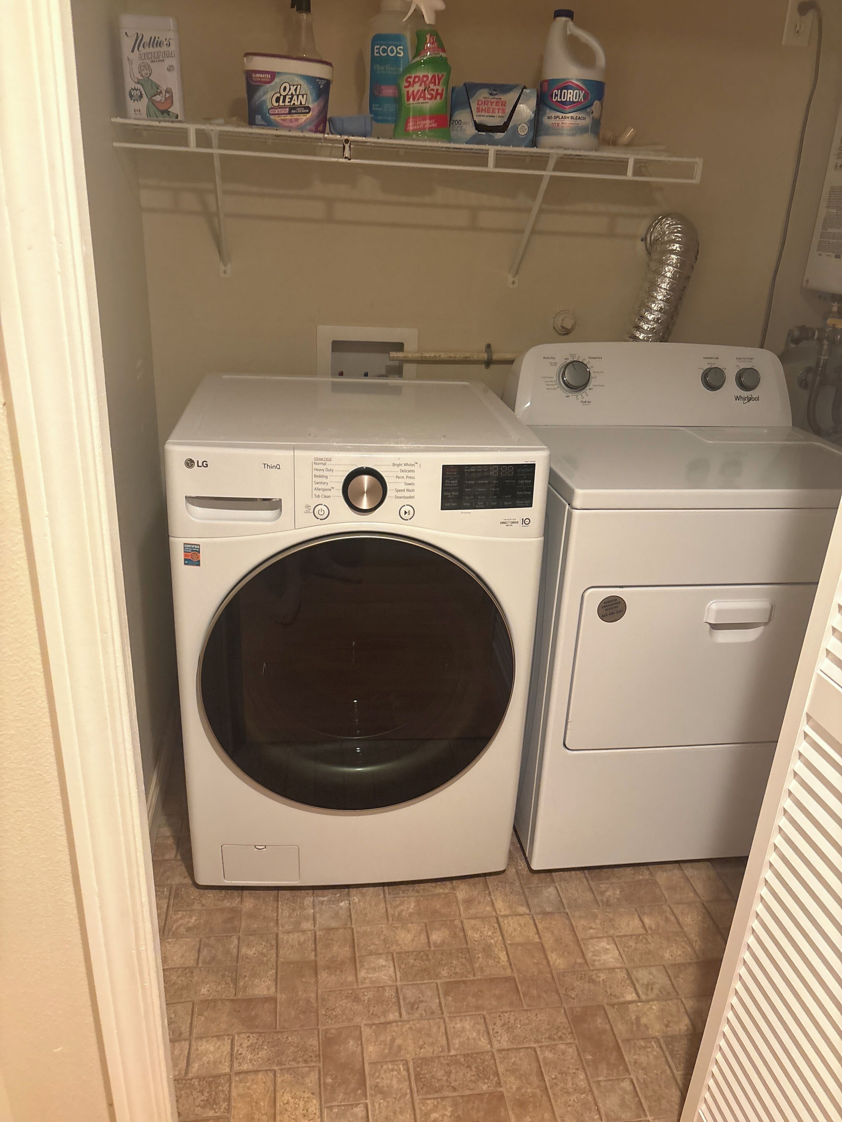 Ein Waschraum mit einer Frontlader-Waschmaschine von LG und einem Toplader-Trockner von Whirlpool.
