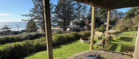 A covered outdoor area with a barbecue grill, wooden benches, and a view of the ocean.