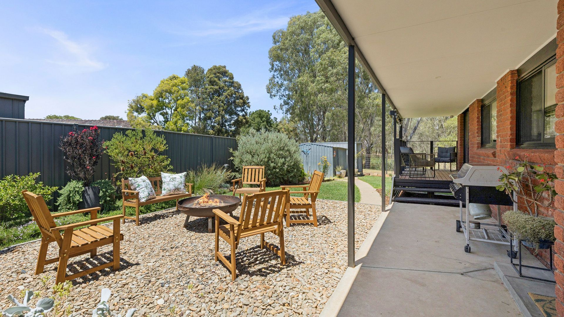 A patio area with wooden furniture, a fire pit, and a barbecue grill.