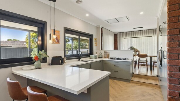 Een moderne keuken met een groot eiland, hanglampen en uitzicht op de omgeving.