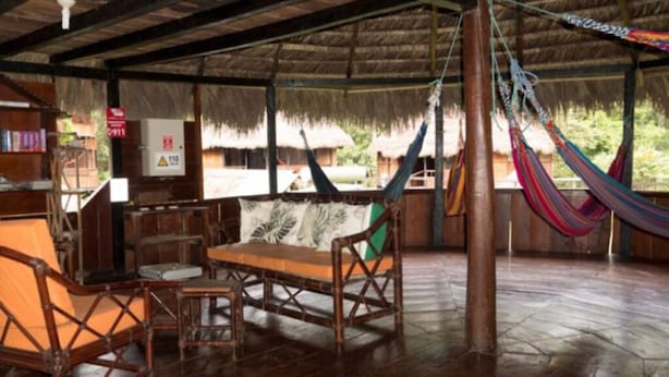 A wooden room with a thatched roof, a hammock, and a wooden table with chairs. - KingFisher Ecolodge (Misahualli)