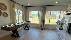 Una habitación amplia con mesa de billar, ventanas grandes y chimenea.