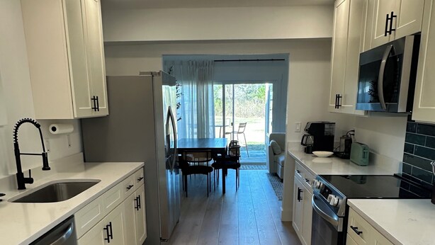 Una cocina moderna con armarios blancos, electrodomésticos de acero inoxidable y una isla central.