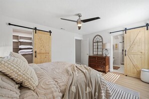 A bedroom with a bed, a ceiling fan, a wardrobe, and a bathroom with a shower. - Lakefront Retreat w/ Private Dock, Kayaks & Sunsets (Odessa)
