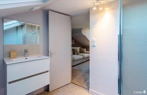 Uma casa de banho moderna com um espelho, lavatório branco e cabine de duche em vidro.